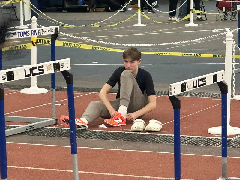 Seamus tying his spikes at an indoor track meet